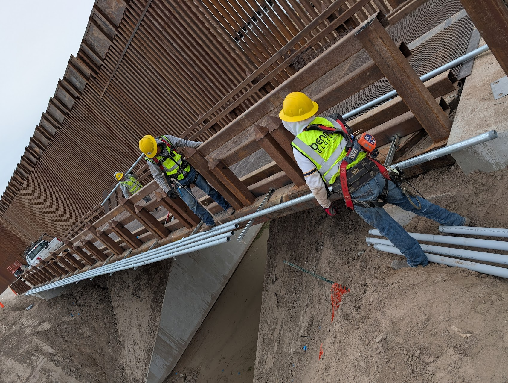 Crew installing conduit under border wall